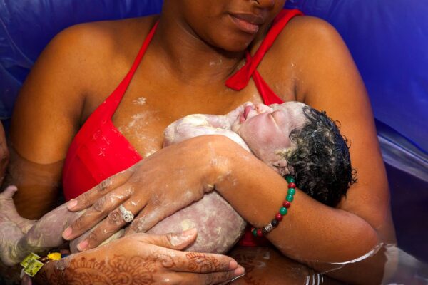 new parent in tub with baby covered in vernix