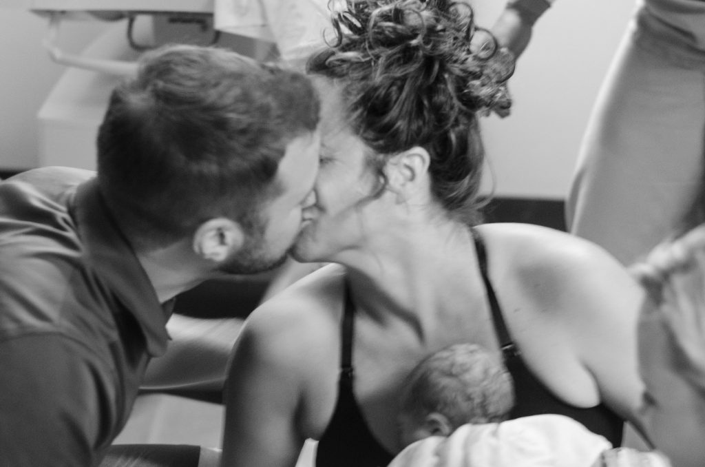 Hypno-mom Lauren holding newborn and kissing partner