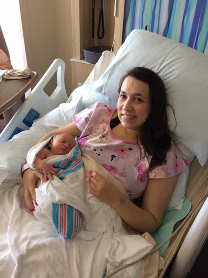 Hypno-mom Nicole in hospital bed smiling and holding newborn daughter.