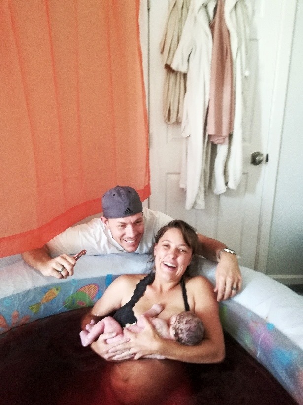 Hypno-mom in birthing tub just after birth holding baby with birth partner