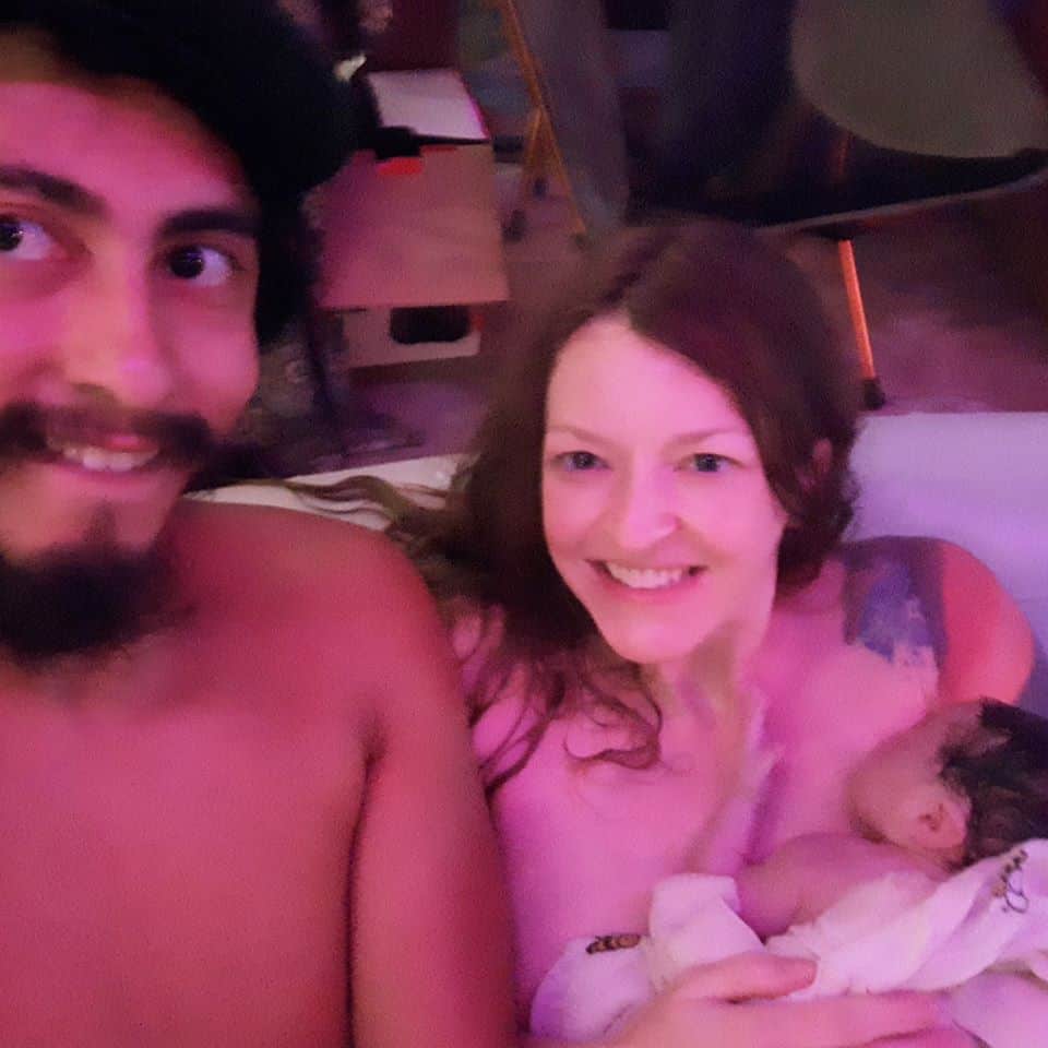 Hypno-mom Jamie in birth tub with partner and holding her newborn