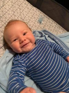 Hypno-mom Emily's baby boy smiling and wearing a blue and white striped onesie.