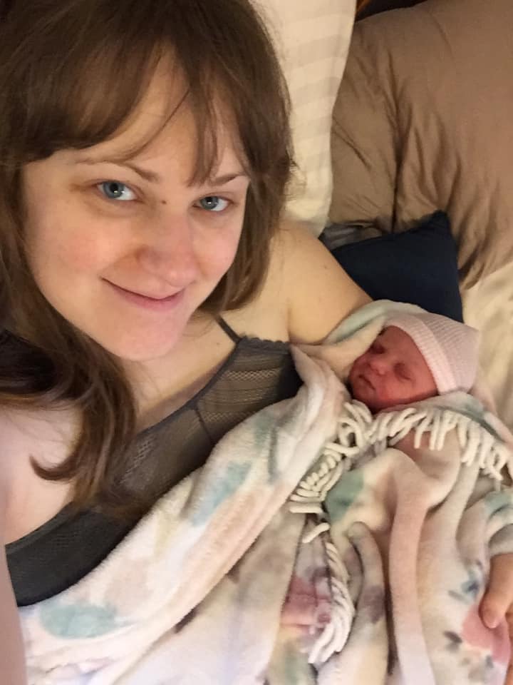 Hypno-mom in bed with newborn baby smiling at camera
