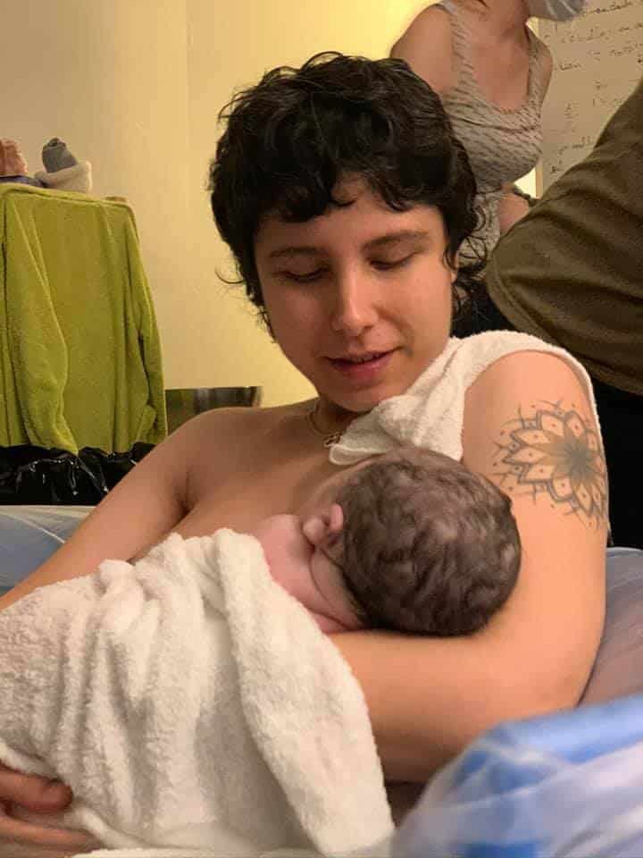 Hypno-mom sitting in birth tub gazing down at newborn baby