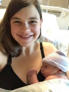 Hypno mom sitting up and smiling holding newborn