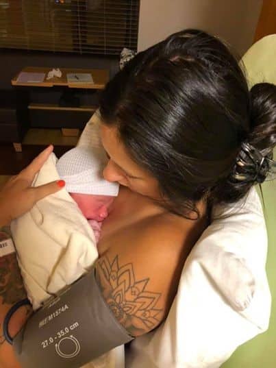 hypno-mom cradling newborn skin to skin and wearing a blood pressure cuff