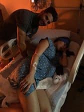 hypno-mom laying on side in hospital bed with partner standing next to her during birthing time