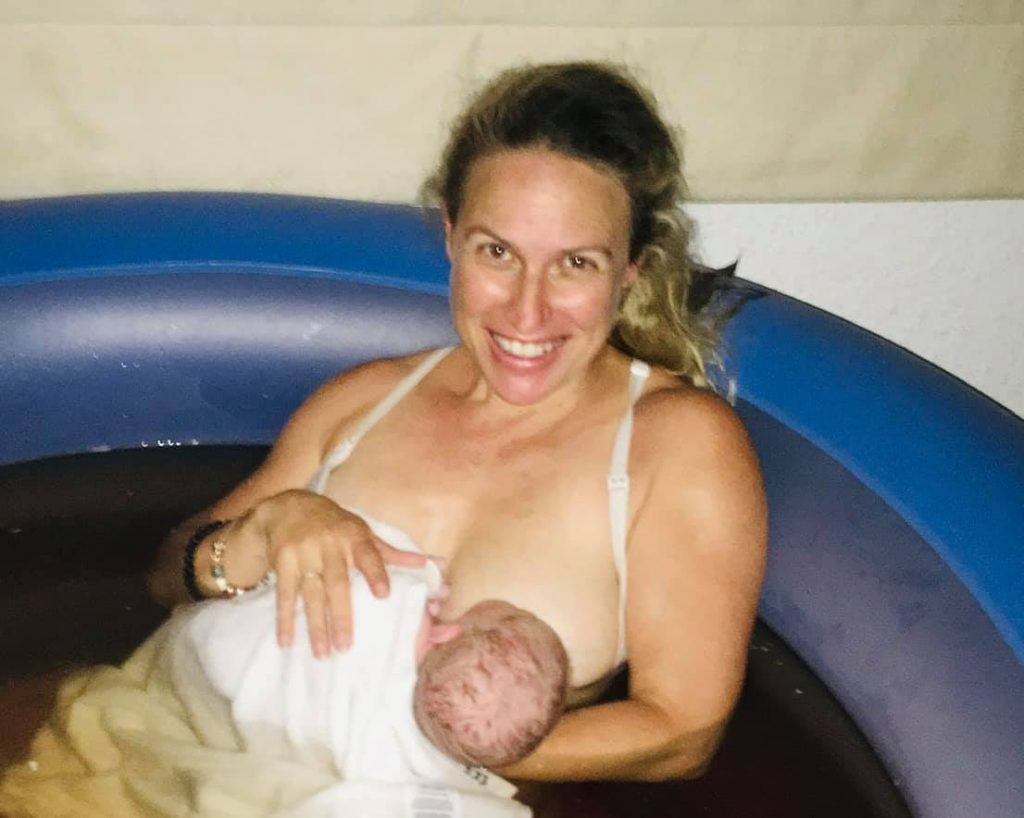 Hypno-mom sitting in birthing tub nursing her newborn baby