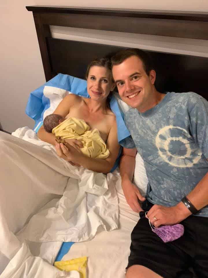 Hypno-mom and partner in bed with newborn baby smiling at the camera