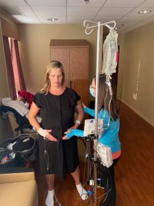 Pregnant person in birthing time holding belly with doula and hooked up to iv