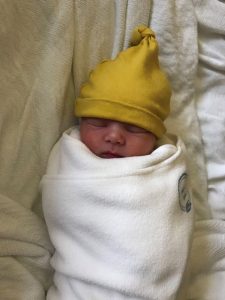 Swaddled newborn with yellow hat