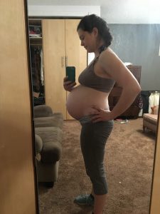 Pregnant person standing sideways in the mirror to show belly