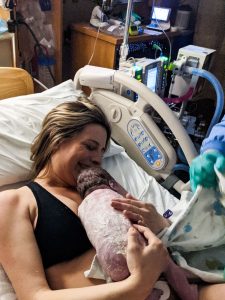 new parent holding newborn covered in vernix right after birth