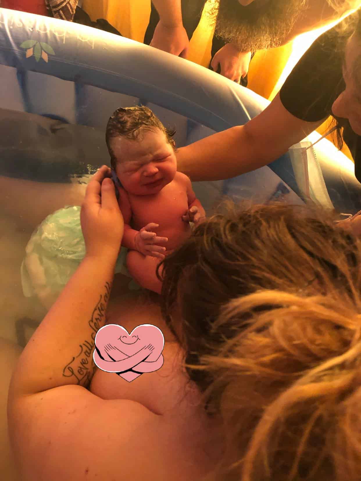 New Parent in birth tub holding newborn baby