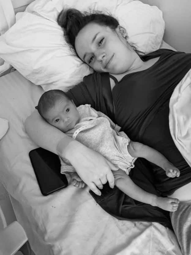 New parent laying in bed cuddling newborn