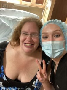 pregnant person and nurse smiling and giving the peace sign