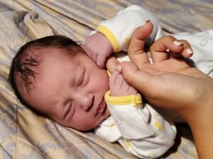 Newborn baby holding a finger