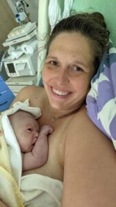 New parent holding newborn skin to skin and smiling