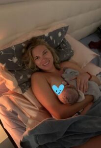 New parent in bed nursing newborn and smiling