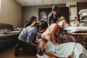 Birthing person pushing with nurse and partner