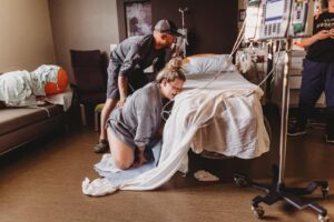 birthing person pushing on hospital floor with partner support