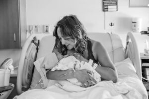 new parent snuggling with newborn baby in hospital bed