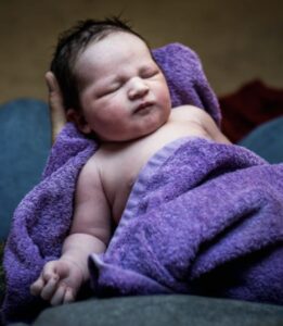 Newborn baby wrapped in purple towel