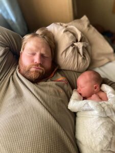 New parent sleeping with newborn baby