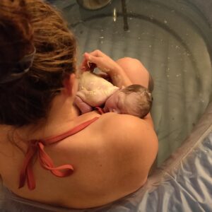 New parent in birth tub skin to skin with newborn
