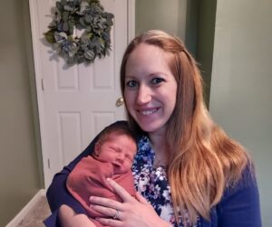 New parent holding swaddled newborn baby and smiling