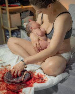 new parent just after birth holding newborn and touching placenta