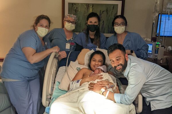 New Hypnobabies parents with newborn baby surrounding by hospital birth team wearing masks