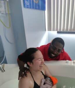Hypnobabies couple smiling with joy in the birth tub with newborn baby