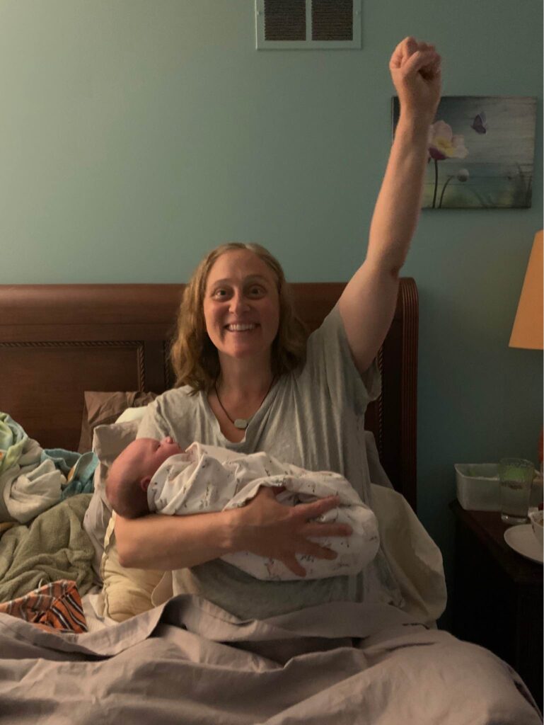 New parent holding newborn baby raising arm in triumph