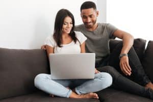 Young couple smiling, looking at the Hypnobabies Online Home Study on their laptop