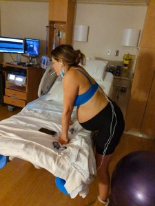 Hypnobabies student standing peacefully and leaning over hospital bed during her birthing time