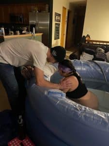 VBAC home birth birthing person in tub with partner assisting