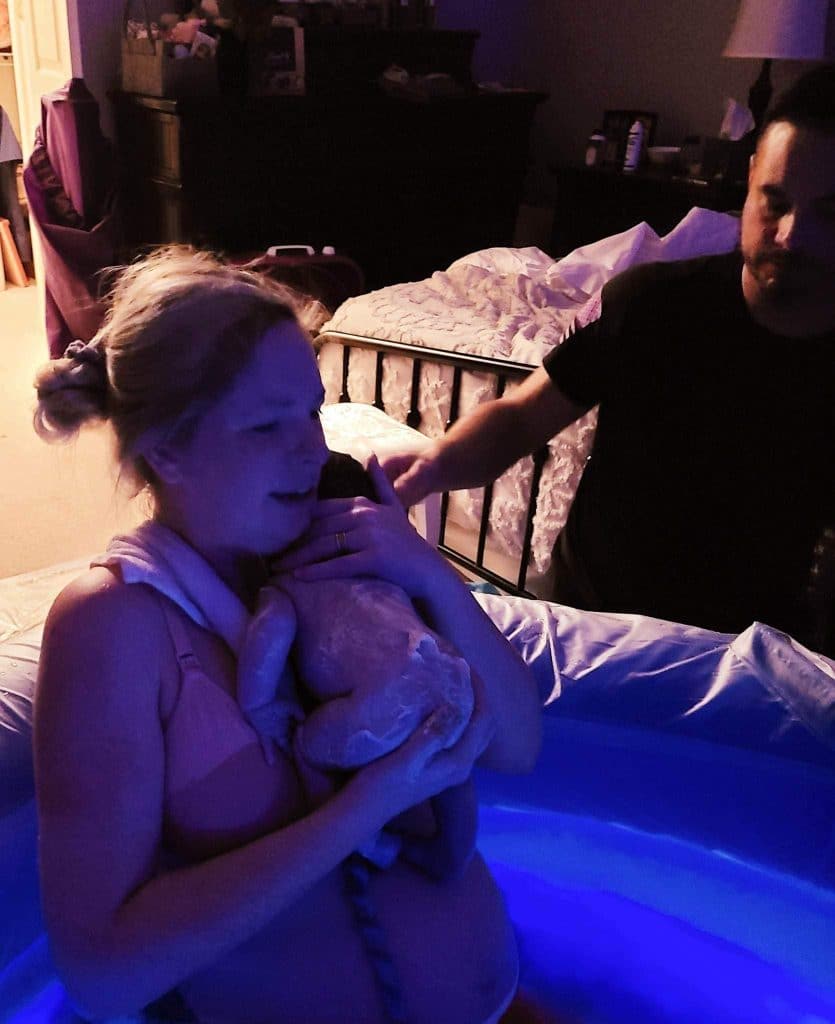 Hypnobabies Student in birth tub holding baby just after empowered home waterbirth