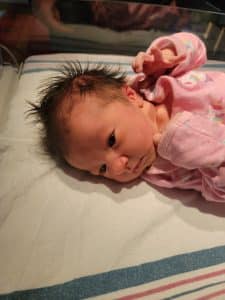 Newborn baby in pink onsie after calm, relaxed birth.