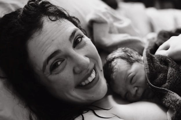 Smiling new parent with newborn baby after Hypnobabies Peaceful Home Birth