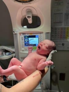 Newborn baby in nurses hands in hospital