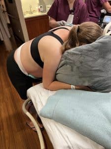 Hypnobabies Student during joyful healing hospital birth leaning over hospital bed