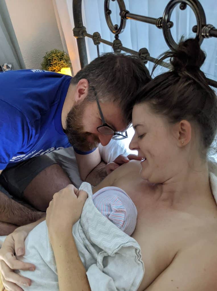 New family in bed with newborn after perfect empowering birth